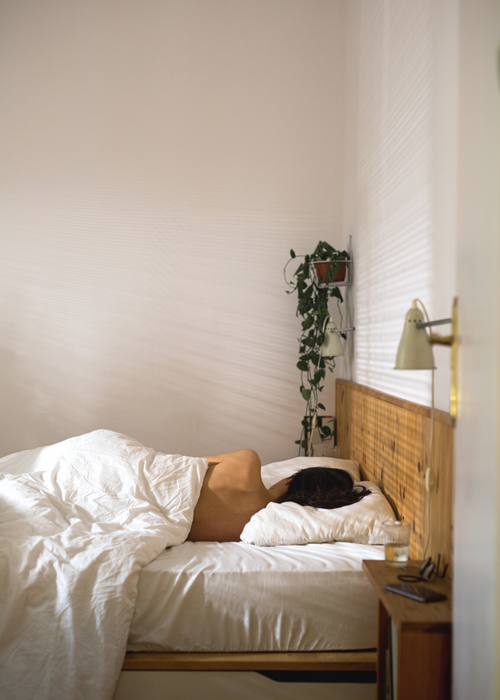 back view of woman sleeping on a bed in the early morning