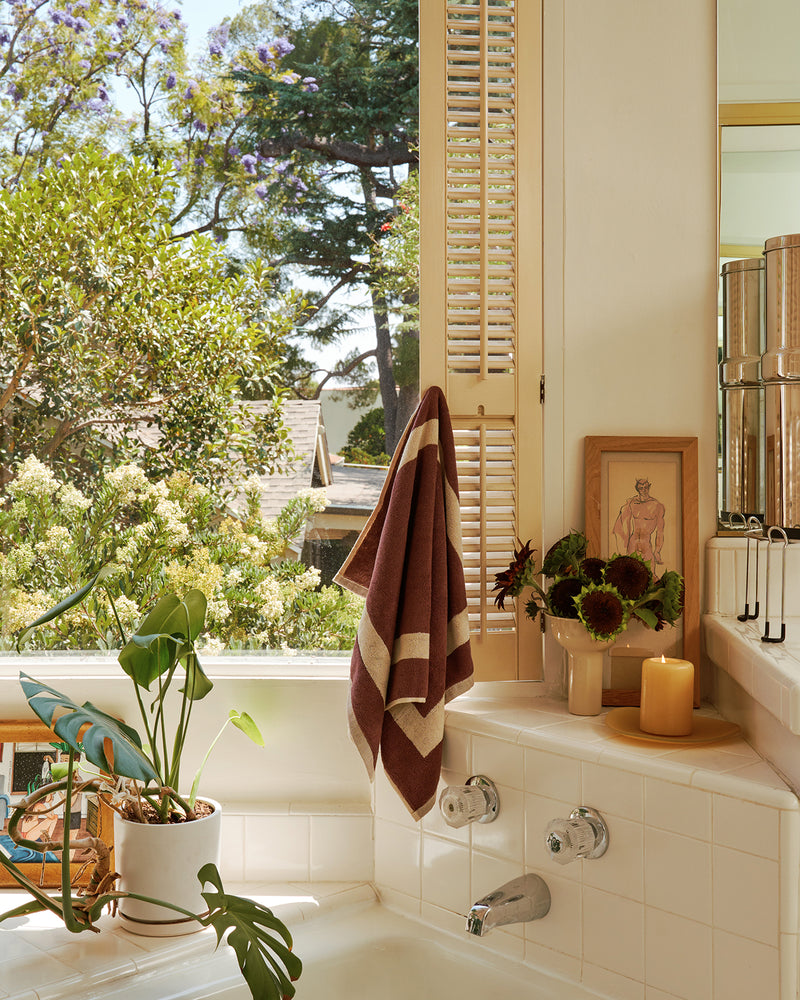 Bathroom with plants, and a window view of trees with the cotton terry two-toned towel in creme and cacao hand towel.