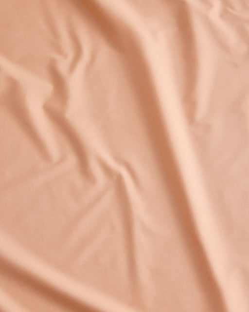 A close-up view of the Butterscotch Organic Cotton ny Bed Threads reveals gentle folds and soft wrinkles, highlighting the luxurious texture of this GOTS certified bedding.