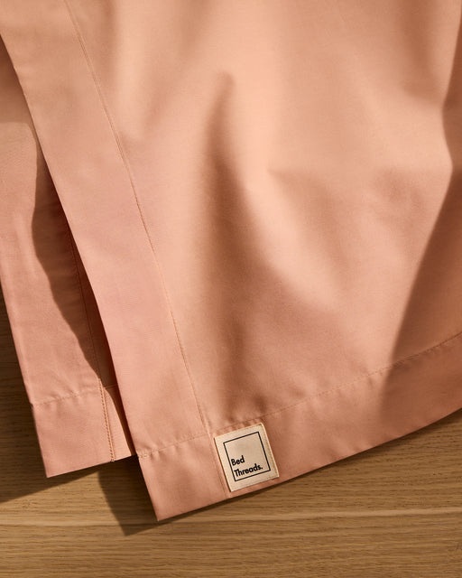 Close-up of the Butterscotch Organic Cotton Flat Sheet by Bed Threads, featuring a small beige label on soft, breathable fabric—ideal bedding for your home.