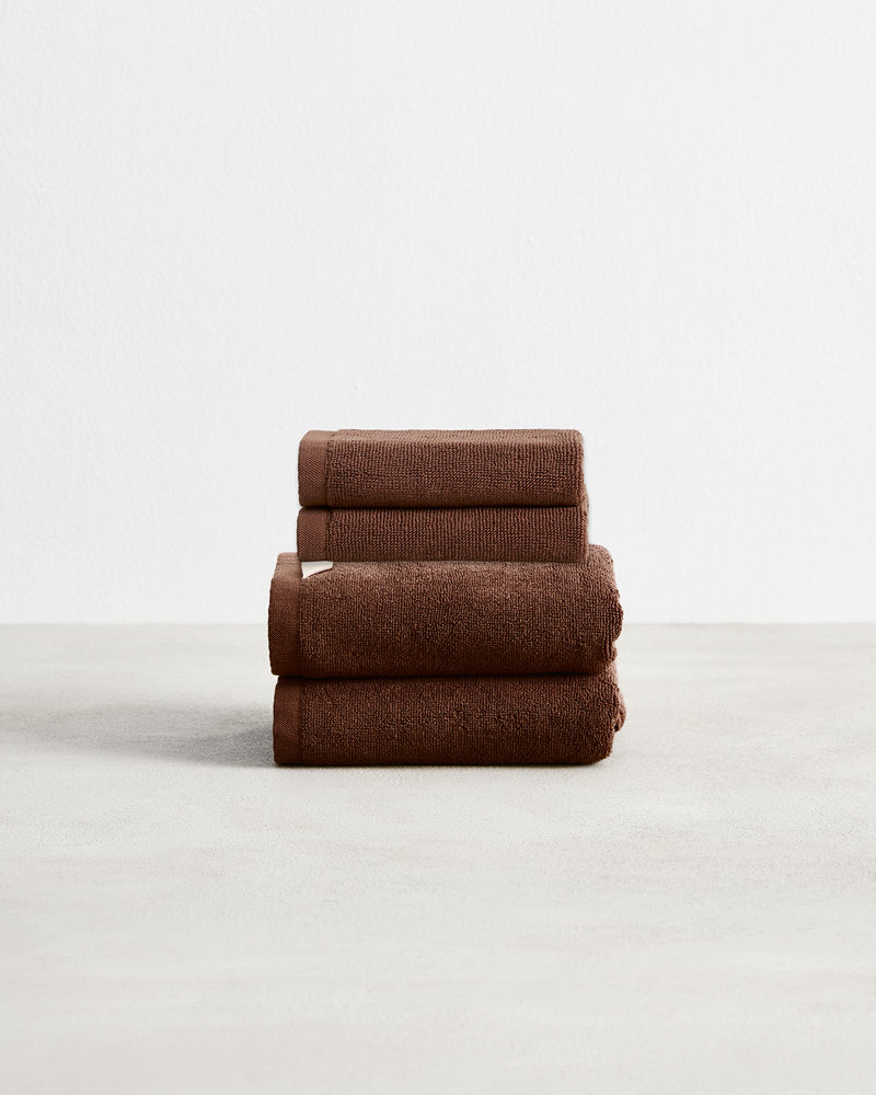 A stack of two, organic cotton terry hand towels and two face washers in an espresso brown shade.