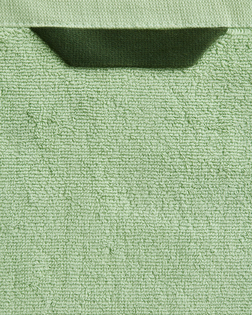 A close-up of the Bed Threads Apple Cotton Terry Bath Towel Bundle in light green, featuring a dark green hanging loop at the top center.