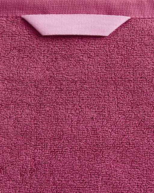 A close-up of the Berry Cotton Terry Bath Sheet by Bed Threads shows its pink textured surface and folded hanging loop, highlighting the plush softness of this cotton bath sheet—ideal for adding luxury comfort to your bathroom.