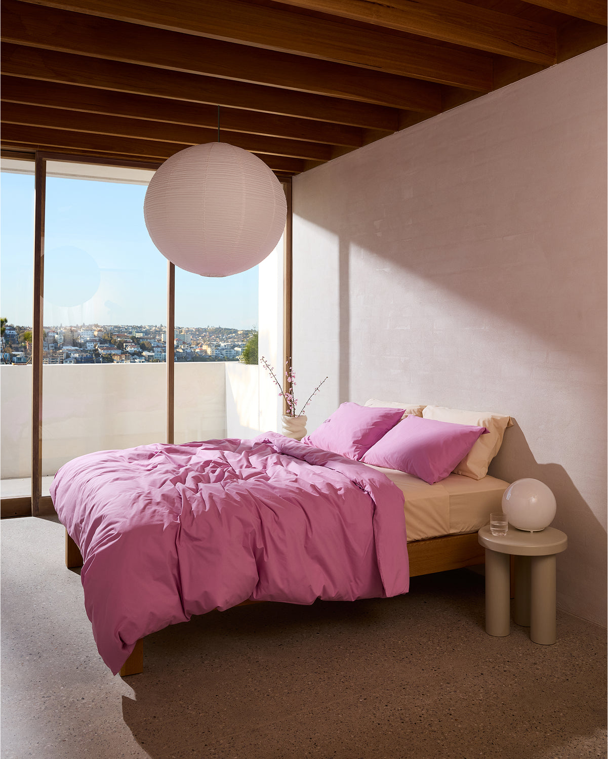 A bed with pink sheets, Bed Threads Bubblegum Organic Cotton King Pillowcases (Set of Two), and a white lamp.