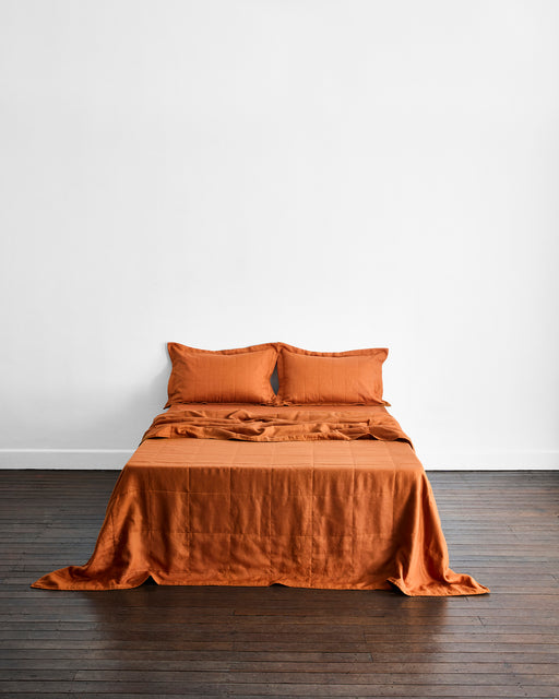 Orange bedding set on a bed against a white wall.