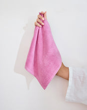 A modern white bathroom sink with a bar of soap, a brush, and two Bubblegum 100% Cotton Terry Face Washers by Bed Threads folded on the countertop. A matching pink bathmat completes the minimal, tidy scene designed to be gentle on skin. - view