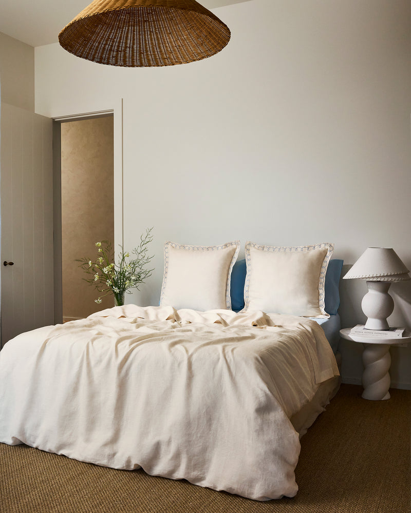 Two Crème & Coast 100% French Flax Linen Swirl European Pillowcases by Bed Threads rest against a light blue headboard, paired with a light beige sheet and soft natural lighting for an inviting look.