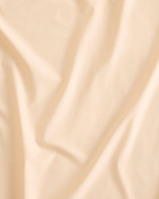 A close-up of Vanilla Organic Cotton by Bed Threads, showing soft, natural folds and gentle creases that create a subtle textured pattern—perfect for your GOTS certified percale bedding.