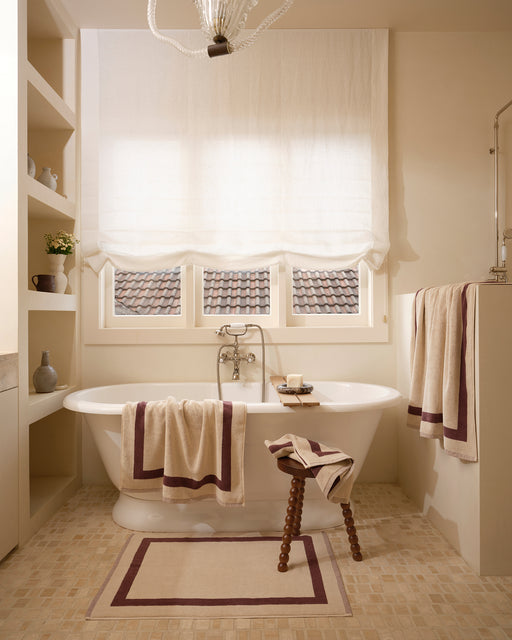Neutral bathroom with freestanding bath tub and cotton terry towels in a creme colour with cacao border.