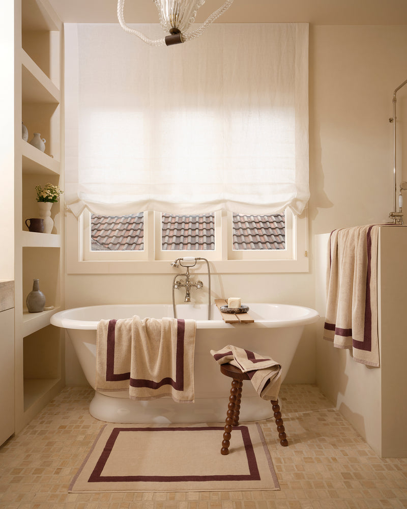 Neutral bathroom with freestanding bath tub and cotton terry towels in a creme colour with cacao border.