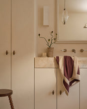Neutral bathroom with cotton terry hand towel in creme and cacao hanging near sink. - view
