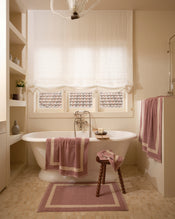 Neutral bathroom with freestanding bath tub and cotton terry towels in a lavender colour with creme border. - view