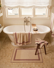 Close up of a freestanding bath tub with cotton terry towels in a creme colour with lavender border. - view