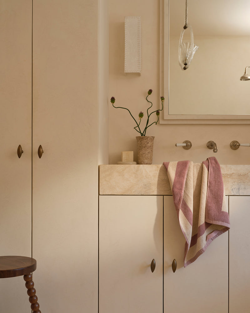 Neutral bathroom with cotton terry hand towel in lavender and creme hanging near sink.