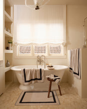 Neutral bathroom with freestanding bath tub and cotton terry towels in an oatmeal colour with charcoal border. - view