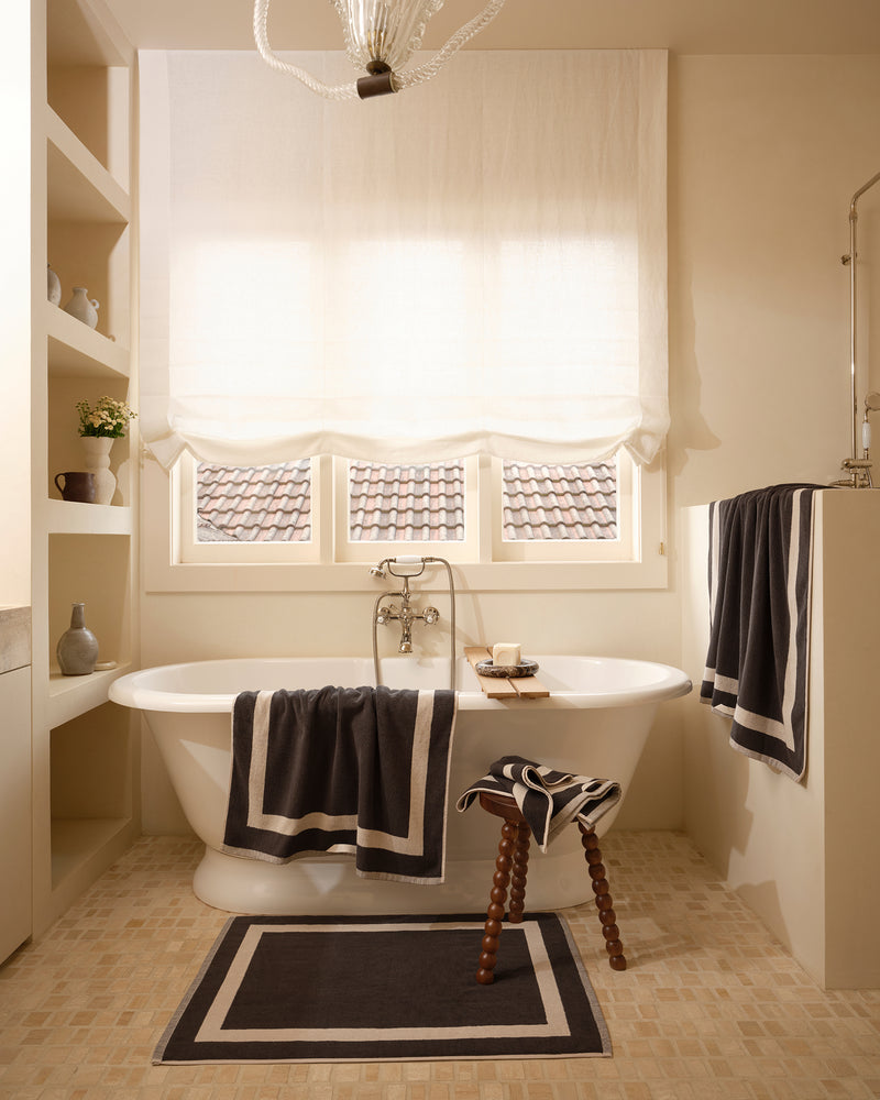 Neutral bathroom with freestanding bath tub and cotton terry towels in a charcoal colour with oatmeal border.