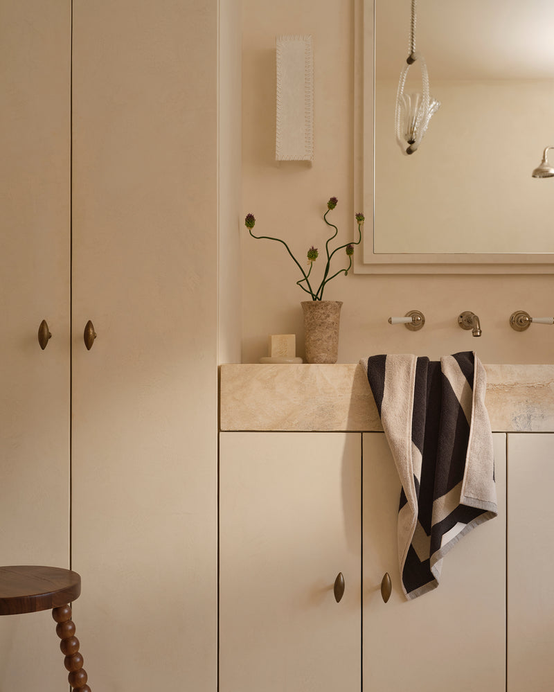 Neutral bathroom with cotton terry hand towel in oatmeal and charcoal hanging near sink.