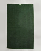 A set of two large, rectangular Moss 100% Cotton Terry Bath Sheets by Bed Threads is displayed flat on a light background. Each dark green towel features a small white tag near the edge and a convenient fabric loop at the top center. - view