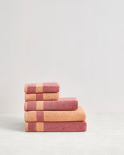 The Bed Threads Terracotta & Pink Clay Two-Toned 100% Cotton Terry Bath Towel Bundle features five folded towels in warm pink tones with stripes, neatly arranged against a plain light background. - view