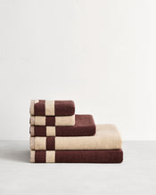 Stack of cotton terry towels in reversible colours creme and cacao. - view