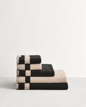 Stack of cotton terry bath sheets in reversible colours oatmeal and charcoal. - view