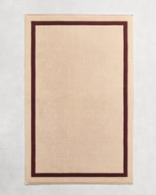 Flat cotton terry bath sheet on a grey background in a creme colour with a cacao border. - view