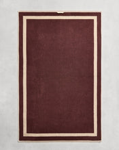 Flat cotton terry bath sheet on a grey background in a cacao colour with a ceme border. - view