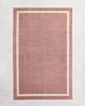 Flat cotton terry bath sheet on a grey background in a lavender colour with a creme border. - view