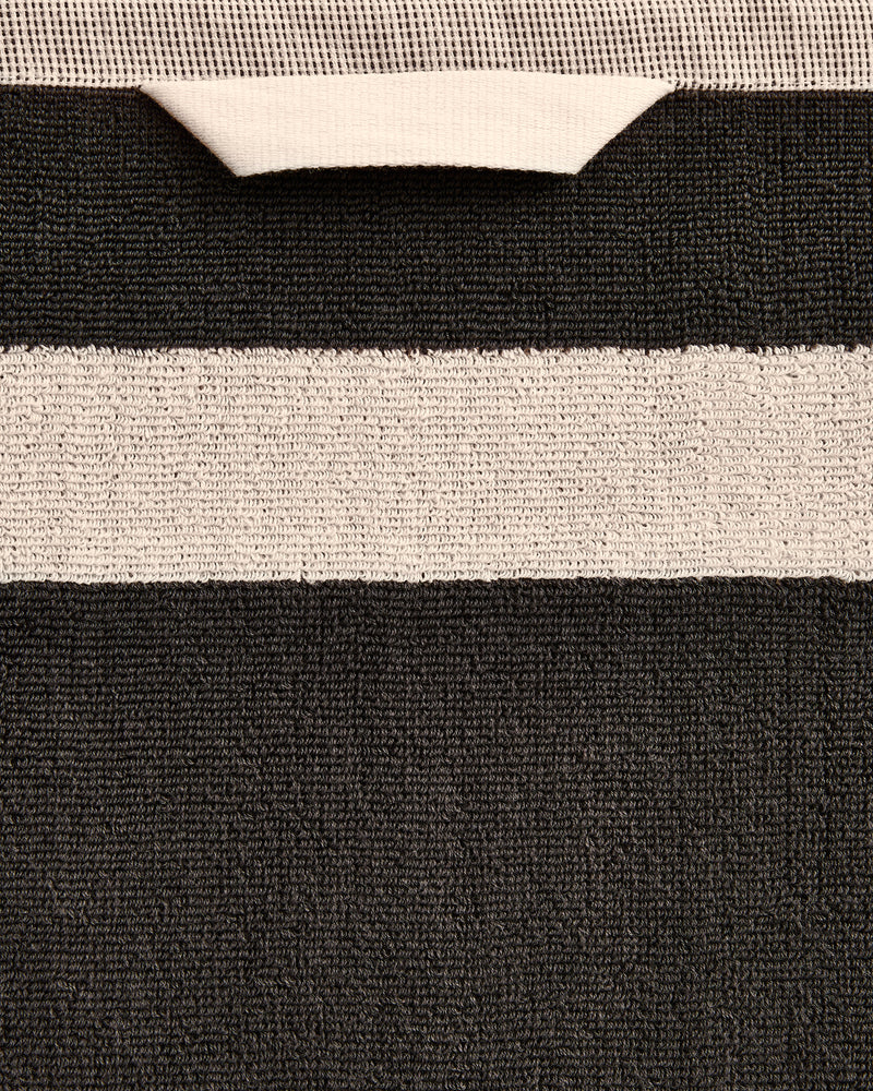 Close-up of a cotton terry towel in a charcoal colourway with an oatmeal border.