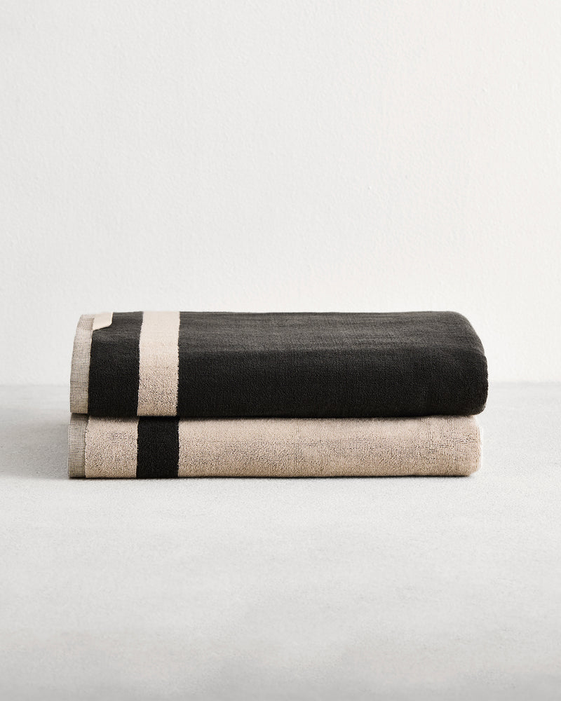 Stack of two cotton terry bath sheets in reversible colours oatmeal and charcoal.