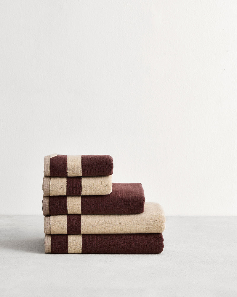 Stack of cotton terry towels in reversible colours creme and cacao.