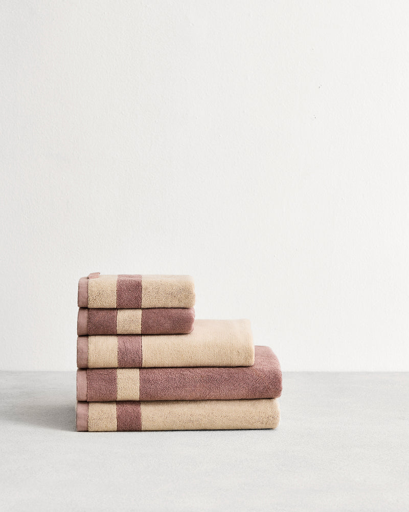 Stack of cotton terry towels in reversible colours lavender and creme.