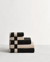 Stack of cotton terry bath towels in reversible colours oatmeal and charcoal. - view