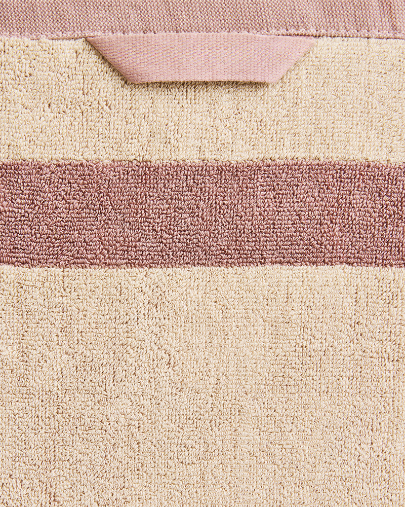 Close-up of a cotton terry towel in a creme colourway with a lavender border.