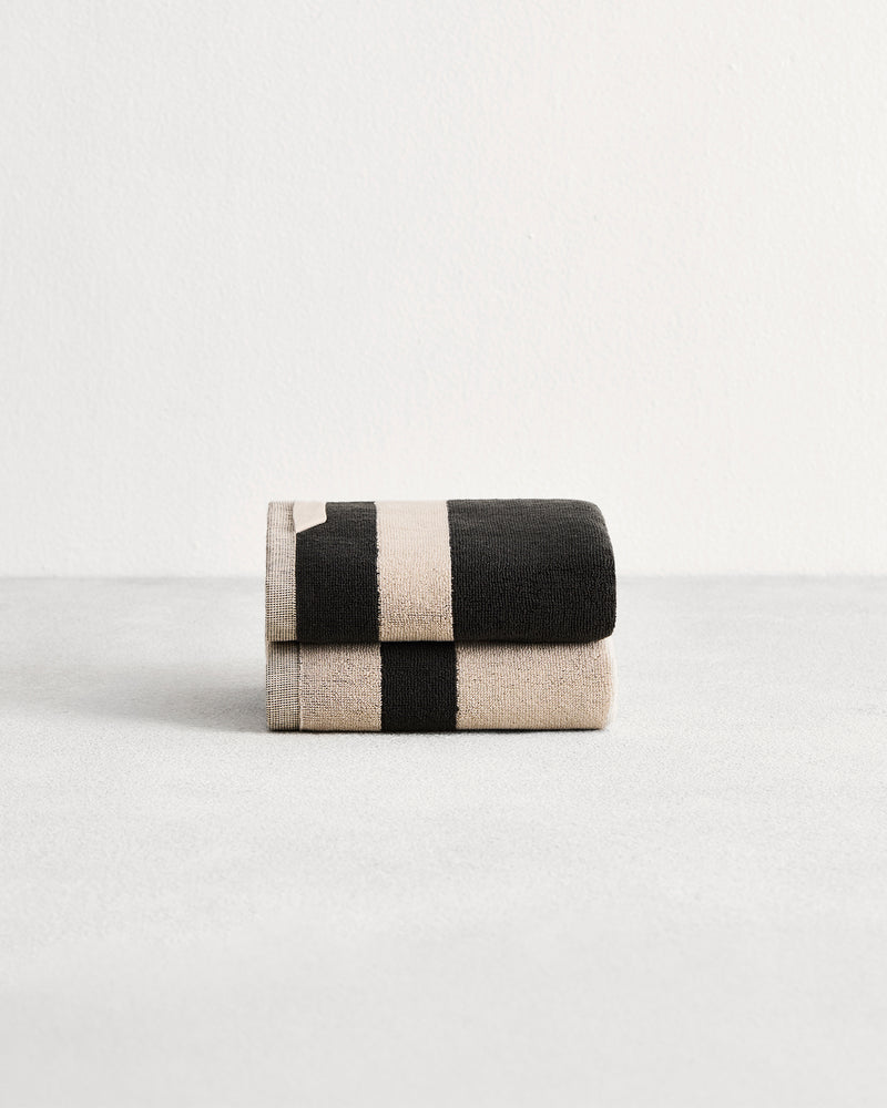 Stack of two cotton terry hand towels in reversible colours oatmeal and charcoal.