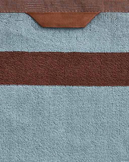 A close-up of Bed Threads’ Cacao & Lagoon Two-Toned 100% Cotton Terry Hand Towels (Set of Two), featuring plush 650GSM light blue cotton with a horizontal brown stripe and a brown trim along the top edge.