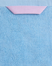 A close-up of Bed Threads’ Sky 100% Cotton Terry Bath Towels (Set of Two), highly absorbent and plush, featuring a pink triangular fabric loop, displayed against a light blue background. - view