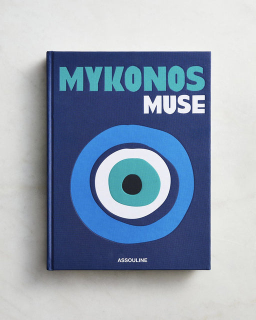 Assouline’s Mykonos Muse by Lizy Manola is a blue hardcover coffee table book with bold text and an evil eye graphic on the cover, celebrating the vibrant spirit of Mykonos.